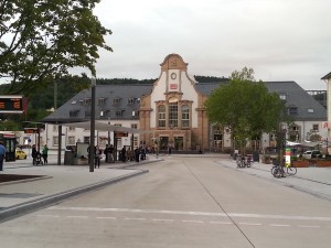 Das historische Bahnhofsgebäude in Marburg aus Richtung der Stadtmitte aus gesehen, davor die neuen Sägezahnanordnungen der Bushaltestellen für die Stadt- und Lokalbuslinien.