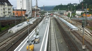 Die Bausphase im Bahnhof Siegen im Juli 2017. Es fährt kein Zug entgegen der Blickrichtung des Fotografen. Mittig des Bahnsteigs stehen die neuen Stützen der zukünftigen Fußgängerbrücke.