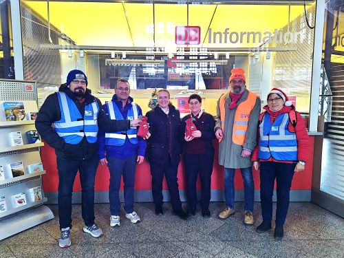 Das Team von PRO BAHN Hessen an der DB Information im Bahnhof Gießen beim Überreichen der roten Geschenkbeutelchen. am 24.12.2025.
